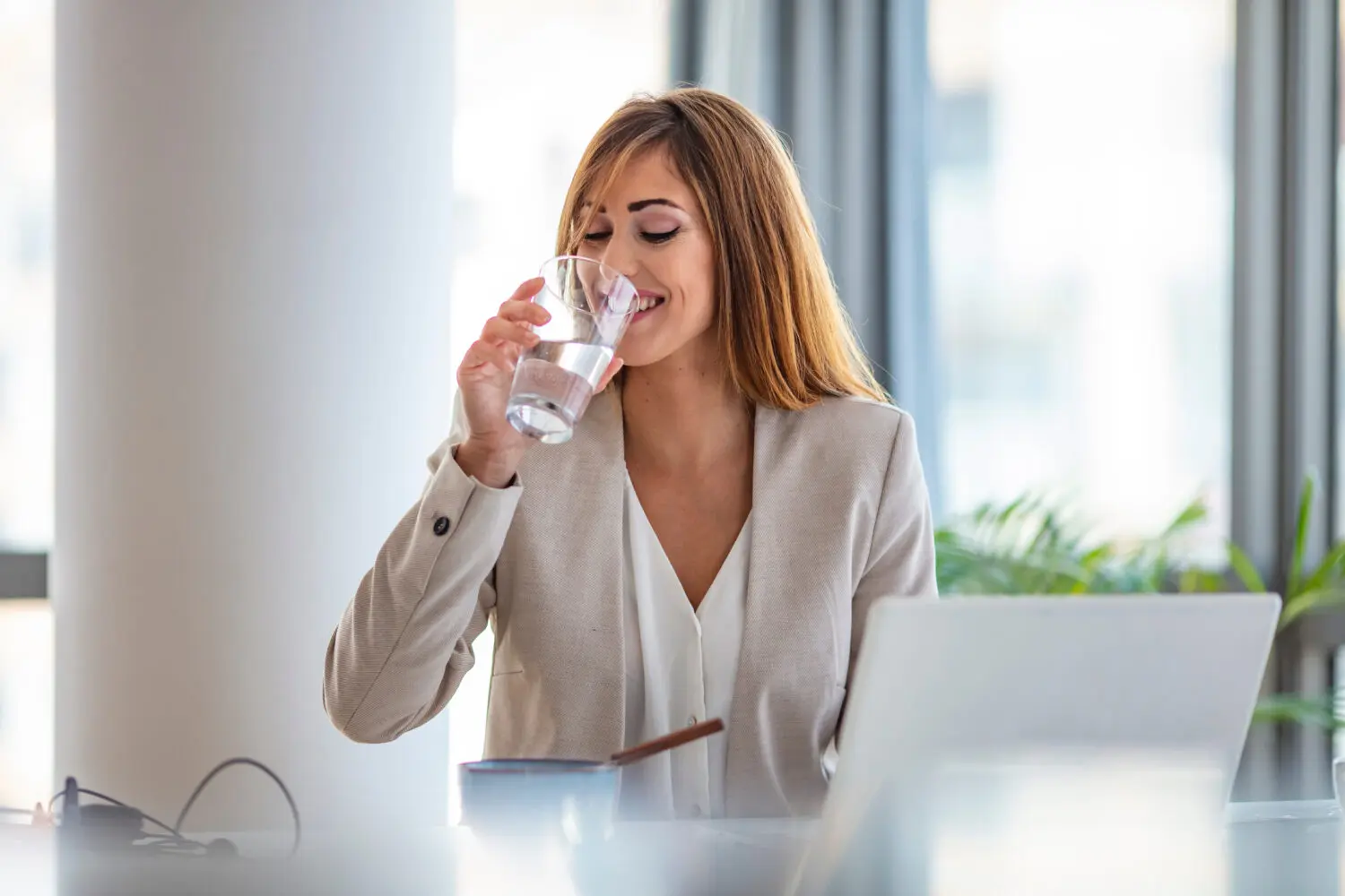 Frau am Arbeitsplatz trinkt Wasser